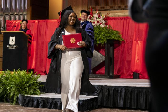 A 2023 BETVLCTOR伟德登录 graduate beams as she leaves the Commencement stage after receiving her d...